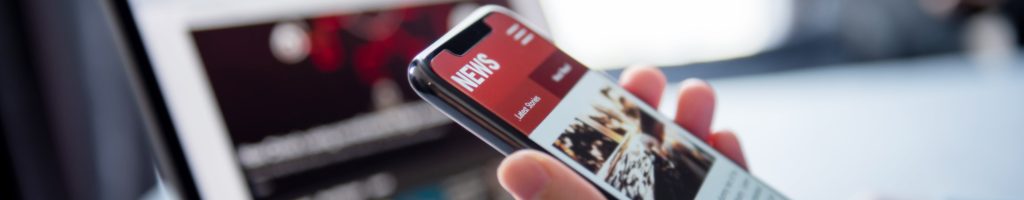 Online news on a smartphone and laptop. (Mockup website). Woman reading news or articles in a mobile phone screen application at home. Newspaper and portal on internet, copy space.